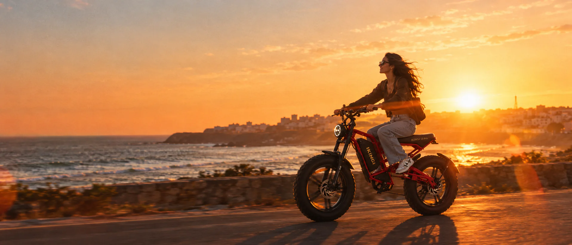 Red IKINGI e-bike on a coastal road at sunset
